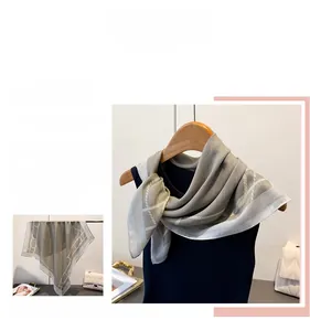 Detail of grey herringbone pattern silk scarf with chain geometric design on a hanger