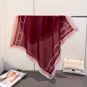 Detail of wine red chain pattern square scarf with elegant drape on a display stand