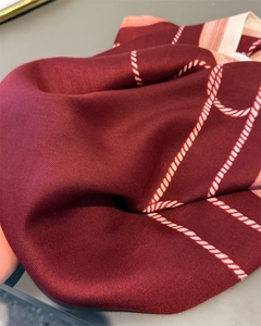 Macro shot of dark red herringbone fabric with white rope print and fine woven texture