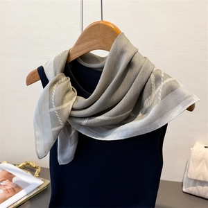 Detailed view of gray silk-like scarf with geometric herringbone patterns on a hanger