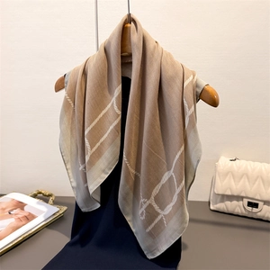 Minimalist khaki silk scarf with white rope pattern hanging on a wooden hanger