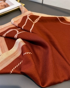 Close-up of terracotta silk-like scarf with white rope patterns and herringbone texture
