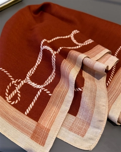 Detail of terracotta silk scarf featuring cream rope pattern and fine twill texture