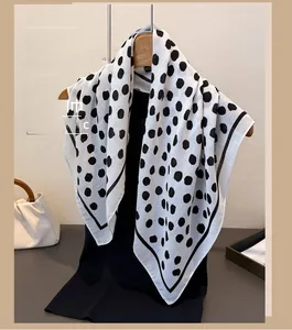 Detailed view of lightweight black polka dot scarf hanging on a wooden hanger