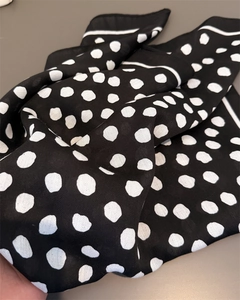 Detailed close-up of classic black and white polka dot pattern on lightweight chiffon scarf