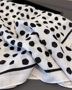 Close-up of lightweight fabric showing black polka dots and fine woven texture details