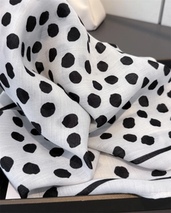 Detail of soft white scarf with black irregular polka dots and textured weave fabric