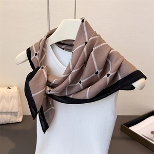 Detail of elegant brown diamond pattern scarf with heart accents draped on a mannequin