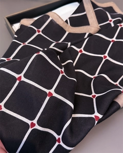 Detailed close-up of plaid square scarf featuring red heart patterns and silk-like texture