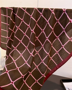 Close-up of brown linen-feel scarf featuring pink grid patterns and red heart embroidery