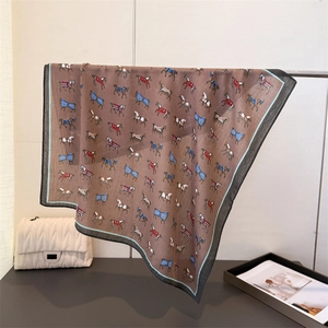 Detail view of brown silk-feel scarf with equestrian horse print and blue border edge