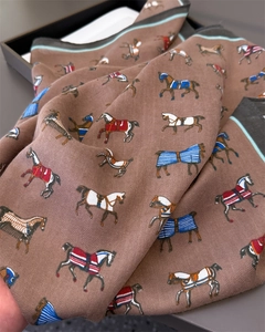 Close-up of luxury herringbone scarf featuring detailed horse print and silky texture