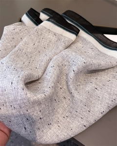 Detail shot of grey linen texture scarf with purple flecks and striped border accents