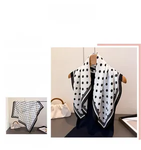 Detailed view of lightweight black and white polka dot scarf draped on a wooden hanger