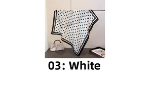 Close-up of elegant white polka dot silk scarf with black geometric border design