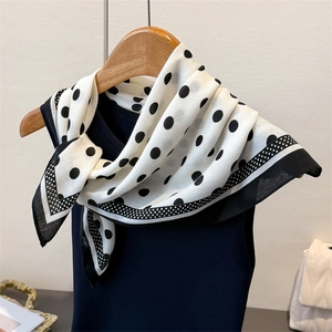 Detailed view of polka dot silk scarf with black contrast borders and elegant drape