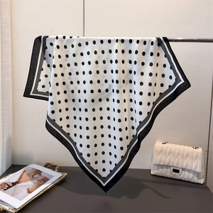 Close-up of a polka dot cotton-linen square scarf hanging on a rack with lifestyle props
