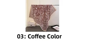 Makro-Detail von braunem Paisley-Vierecktuch kombiniert mit einer gesteppten Handtasche