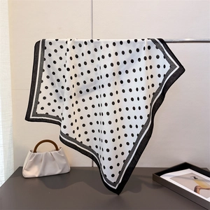 Close-up of lightweight polka dot scarf hanging on metal bar with soft draping
