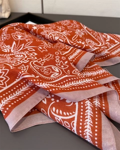 Detailansicht eines orangefarbenen Paisley-Schals mit feiner Textur und eleganten Falten