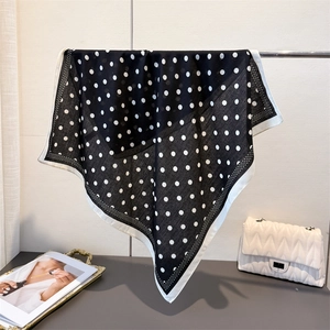 Detail of classic black and white polka dot silk scarf with wide white hem and smooth texture