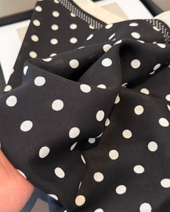 Close-up of black herringbone fabric with white polka dots and soft texture detail