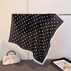 Close-up of a classic black and white polka dot silk scarf with wide white borders