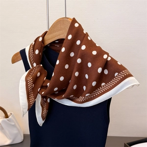 Detail of caramel brown polka dot scarf with white geometric mesh patterned borders