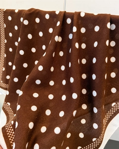Detail of brown polka dot scarf with geometric pattern border and soft fabric texture