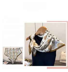 Detail view of the paisley silk scarf featuring gold and brown floral patterns and smooth texture