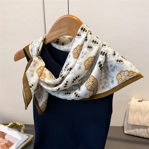 Elegant herringbone silk scarf with floral pattern and brown trim on a hanger