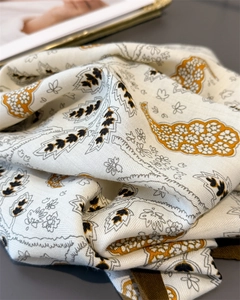 Close-up of herringbone texture on cotton-linen scarf with golden leaf and paisley patterns