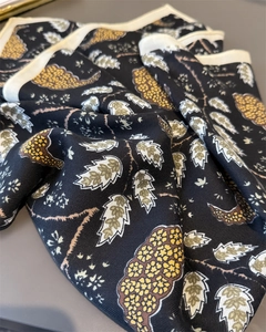 Detailed view of black herringbone silk scarf with yellow floral print and cream hem