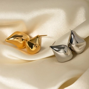 Détail de boucles d'oreilles goutte en or 18 carats et argent sur fond de soie beige