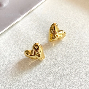 Golden heart earrings with LO embossed letters on white leather background