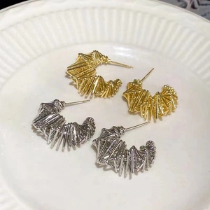 Detailed view of silver and gold irregular spring hoop earrings with geometric textures