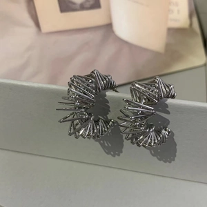 Detailed view of silver bird nest earrings with irregular spiral wire design and 3D texture