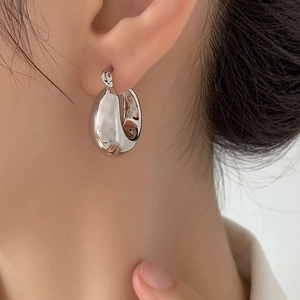 Close-up of polished silver teardrop earrings worn by a model in a minimalist style