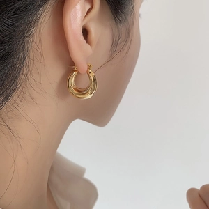 Close-up of elegant 18K gold plated oval hoop earrings worn by a female model