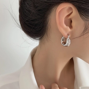Close-up of irregular textured silver hoop earrings on model for a modern aesthetic