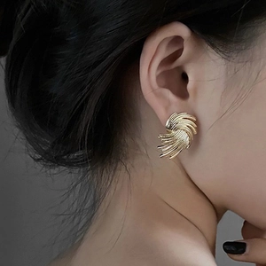 Close-up of golden spiral weave stud earrings on model showing detailed metal texture