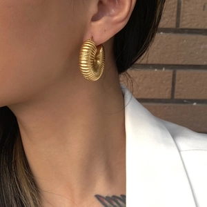 Détail de boucles d'oreilles créoles plaquées or 18K à texture spirale sur un mannequin