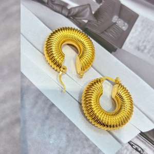 Détail de boucles d'oreilles créoles plaquées or avec textures horizontales fines