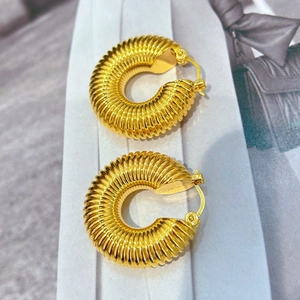 Gros plan de boucles d'oreilles créoles dorées 18 carats avec texture striée épaisse