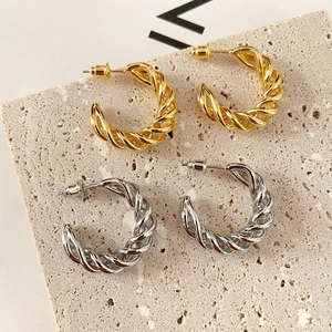 Detailed view of 18K gold and silver twisted hoop earrings on stone display board