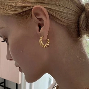 18K gold plated twisted hoop earrings with a textured spiral design on a female model