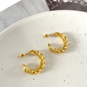 Macro detail of 18K gold plated twisted hoop earrings with a polished metal texture