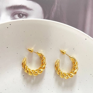 Detailed view of 18K gold plated twisted rope hoop earrings on decorative tray