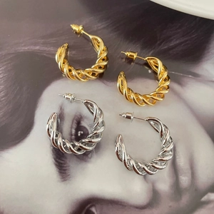 Detail view of gold and silver twisted hoop earrings with elegant spiral texture
