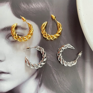 Detailed view of twisted rope hoop earrings in polished gold and silver metal finishes